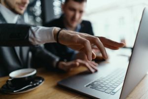 two-businessmen-pointing-laptop-screen-while-discussing-scaled